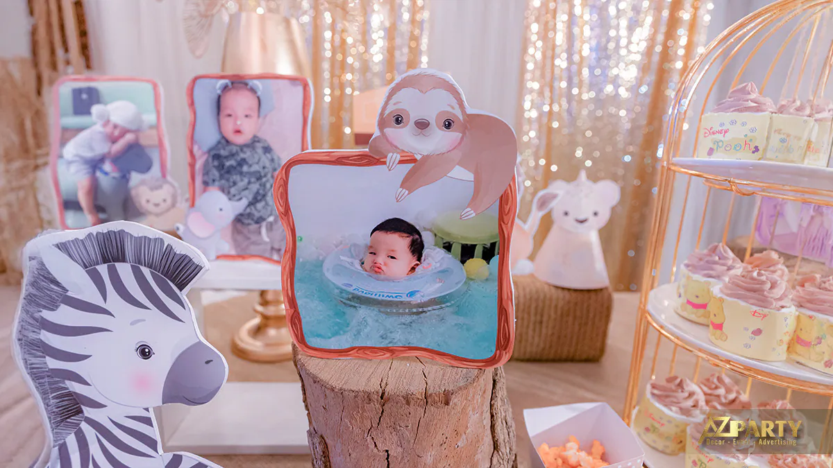 Góc decor bàn tiệc thôi nôi trưng bày những bức ảnh ngộ nghĩnh của bé trong khung hình thú