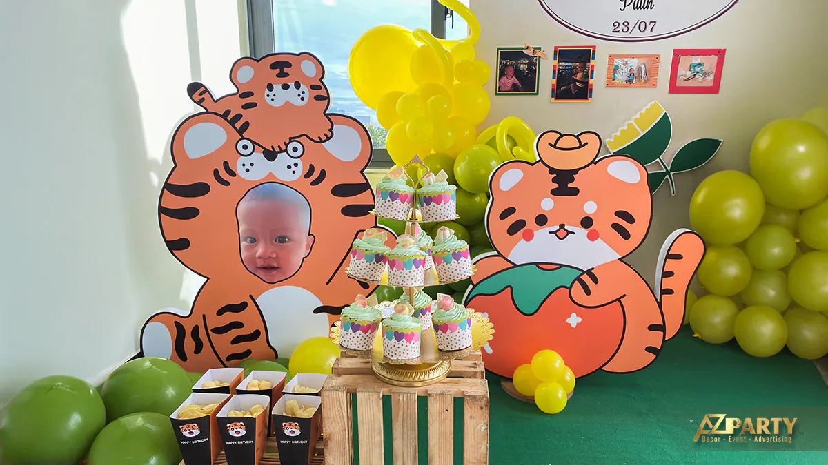 Tháp bánh cupcake xinh xắn đặt trên kệ gỗ mộc mạc bên cạnh mô hình ghép ảnh bé Putin đáng yêu trong bộ đồ con hổ