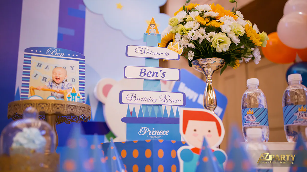 Bàn trang trí tiệc thôi nôi bé Thái Thịnh ngập tràn phụ kiện đáng yêu như bình hoa hướng dương, chai nước thiết kế riêng và tháp lâu đài