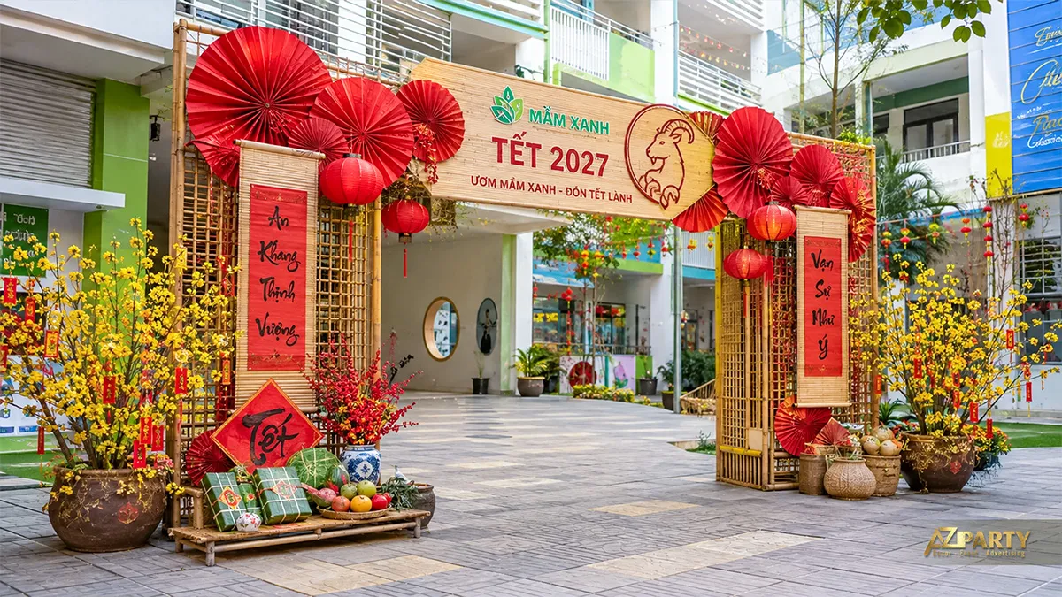 Cổng Tết trường Mầm Xanh với khung tre, quạt đỏ, câu đối, hoa mai và mâm ngũ quả