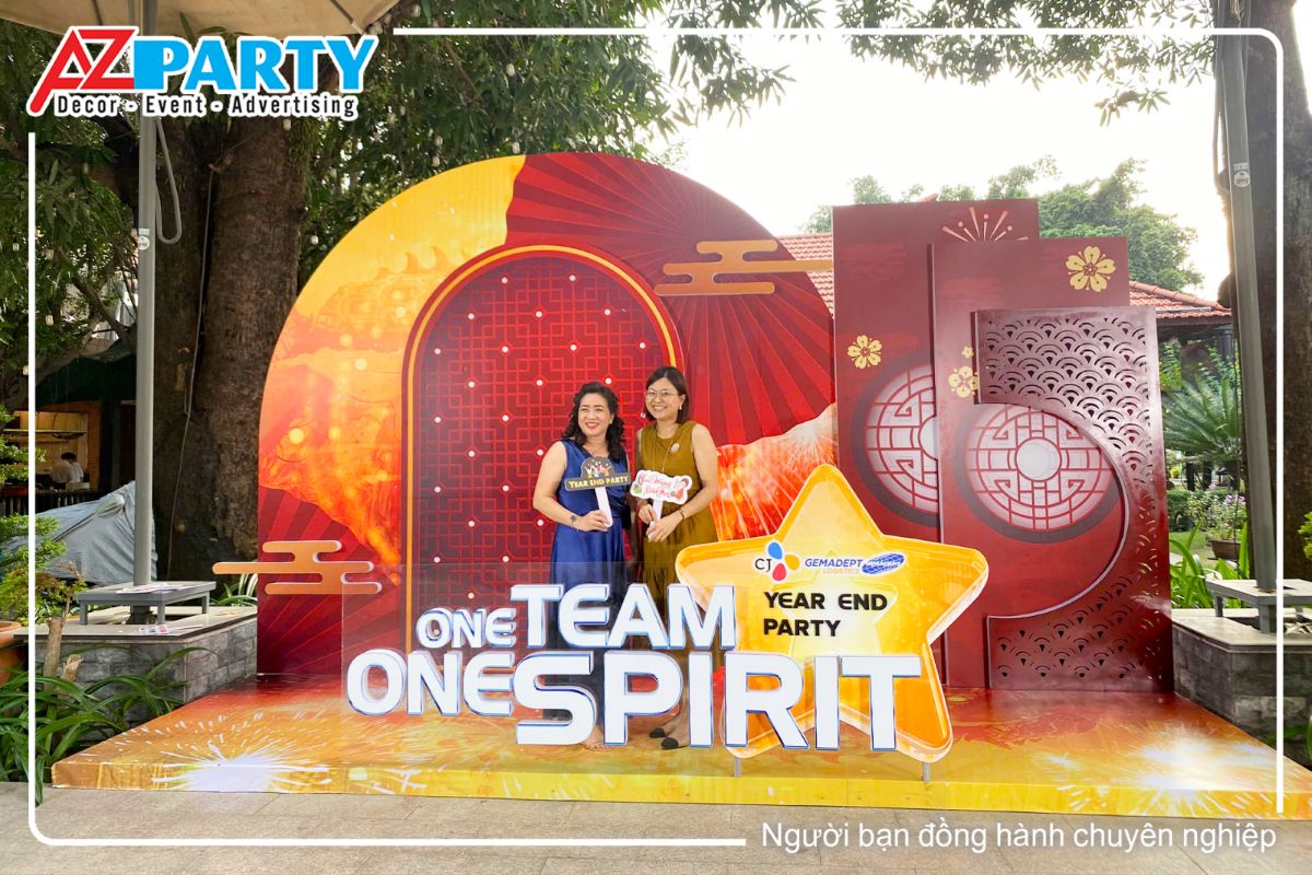 Booth check in YEP công ty Gemadept theo tone vàng đỏ, vách lưng làm theo các hoạt tiết xưa với cửa trong, nhiều hình vảy cá. Trước booth là câu slogan One team one spirits cùng logo của thương hiệu công ty