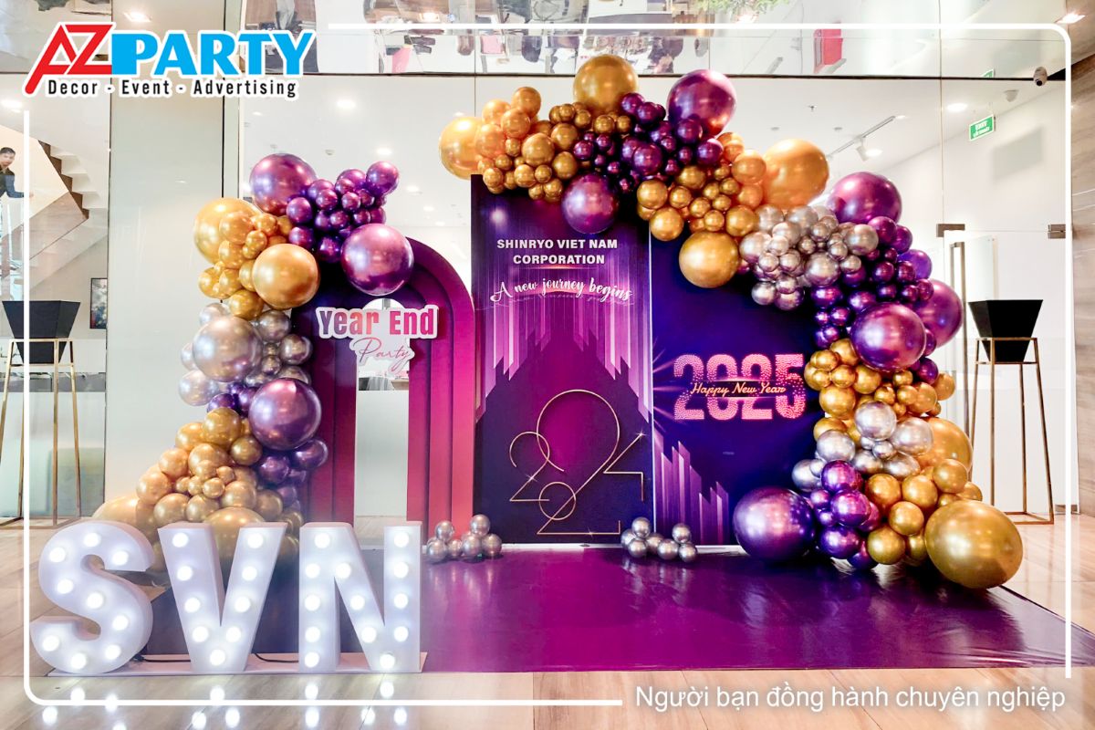 Booth check tin tất niên công ty Shinryo, tone tím chủ đạo, 2 bên là line bóng vàng và tím, bên trái là tên thương hiệu hình 3D của công ty, sàn trải bằng hiflex