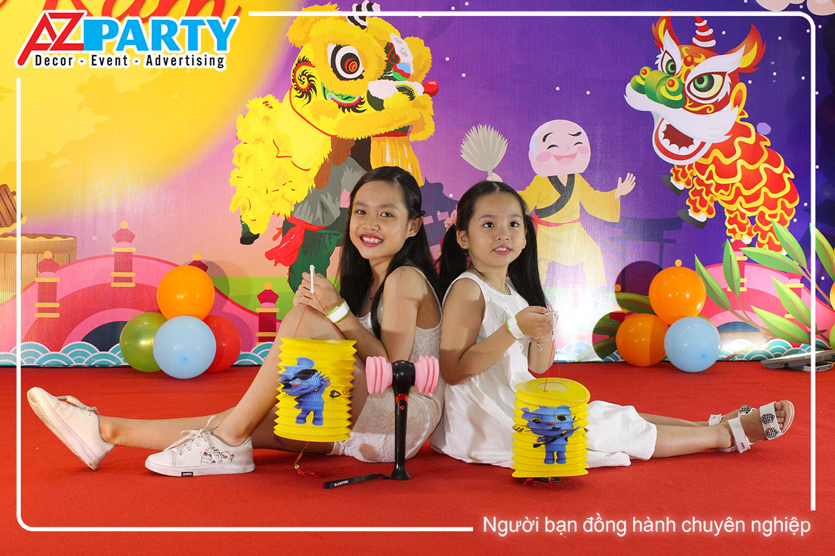 2 em bé chụp hình trên sân khấu, trên tay cầm đèn lồng trung thu