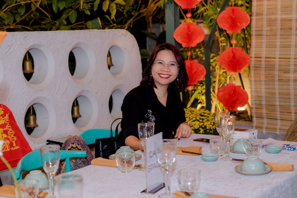 1 nhân viên nữ tươi cười ngồi tại bàn tiệc tất niên của C.A.M Holdings