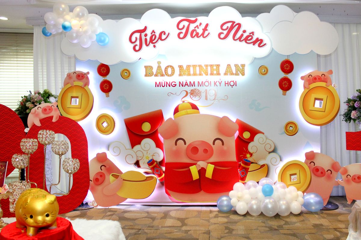 backdrop tiệc tất niên Công Ty Bảo Minh An, nổi bật với sắc đó và vàng của hú heo mập cùng những đồng tiền vàng may mắn