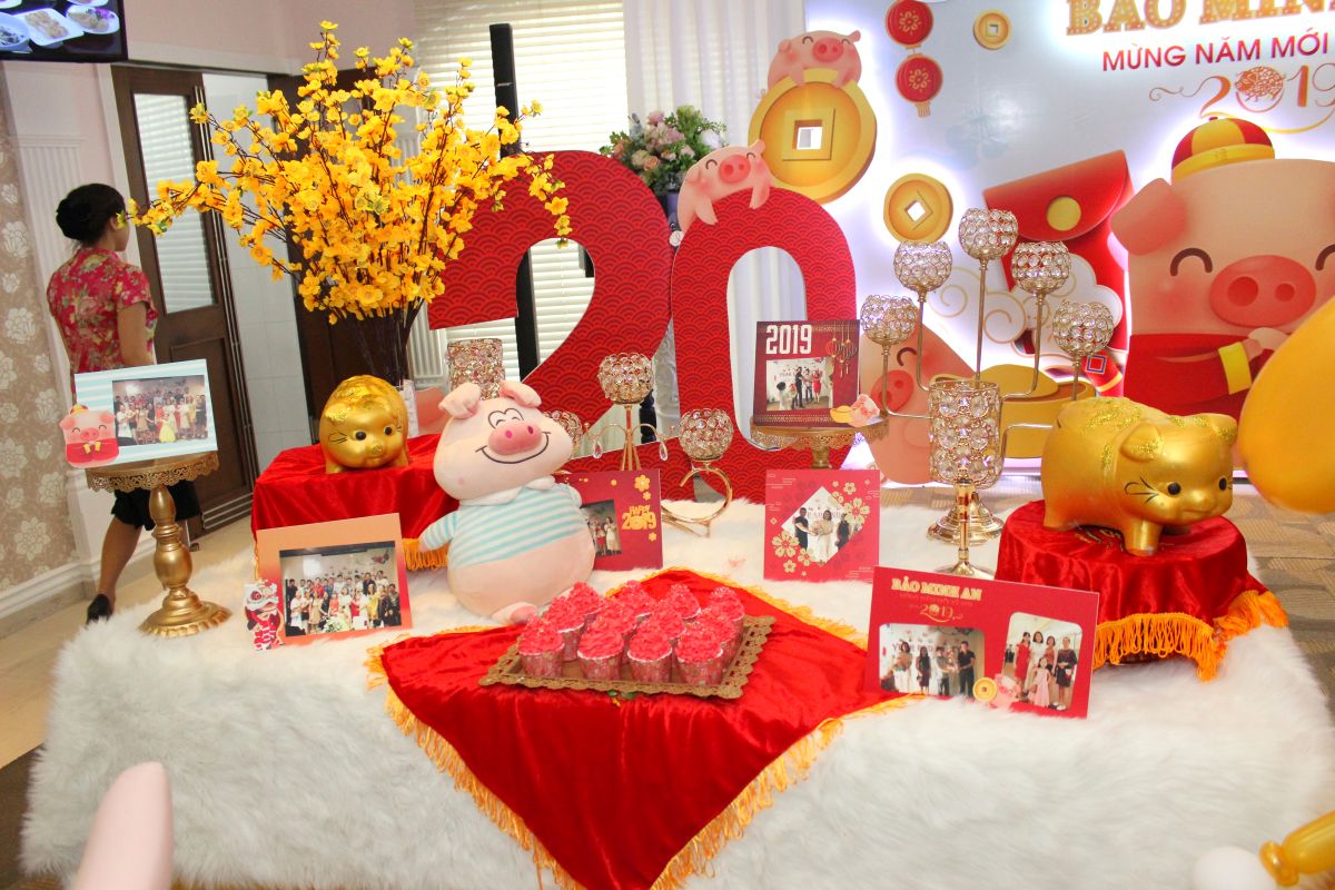 bàn gallery, trên bàn được trang trí những chú heo (linh vật năm) cùng những bức hình tập thể của Bảo Minh An