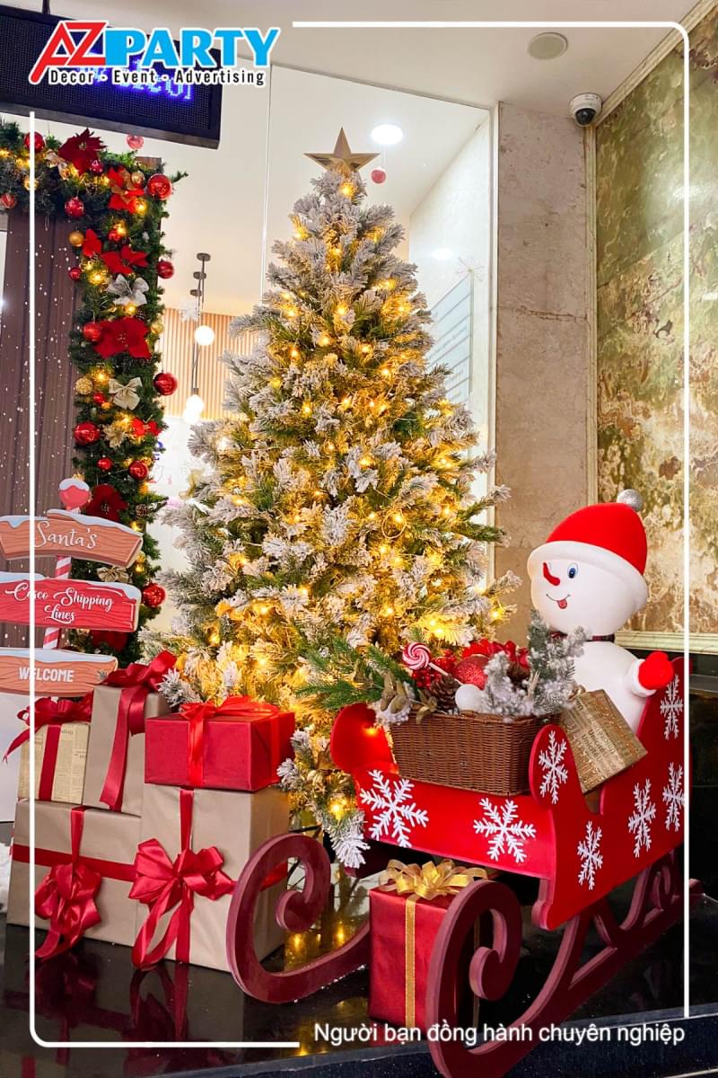 Cây thông noel vàng, dưới gốc cây là những hộp quà và chú người tuyết