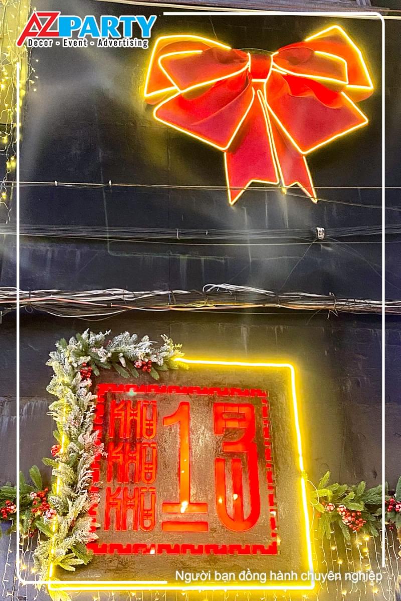 chiếc nơ đỏ khổng lồ có đèn neon bao quanh, bên dưới là logo của khu 13 club