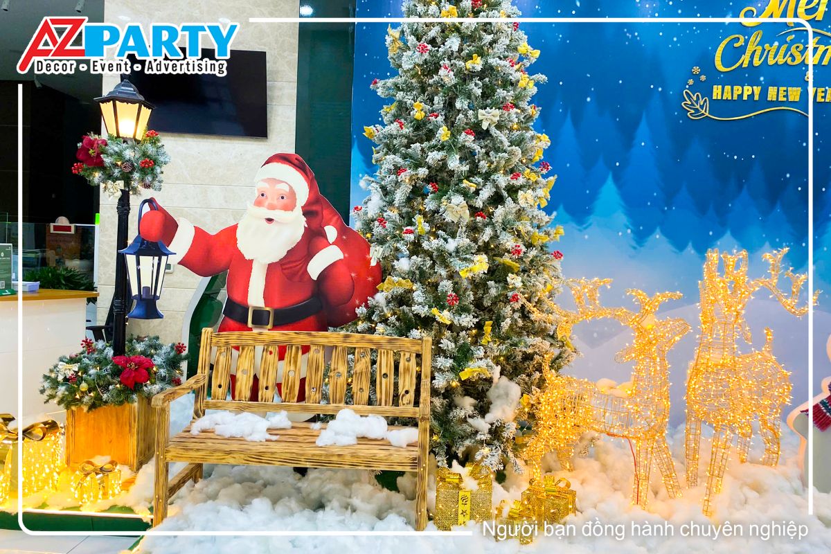 Cận cảnh ông già noel đứng cạnh cây thông, bên cạnh là cặp đôi tuần lộc, trước mặt là ghế gỗ để ngồi check in