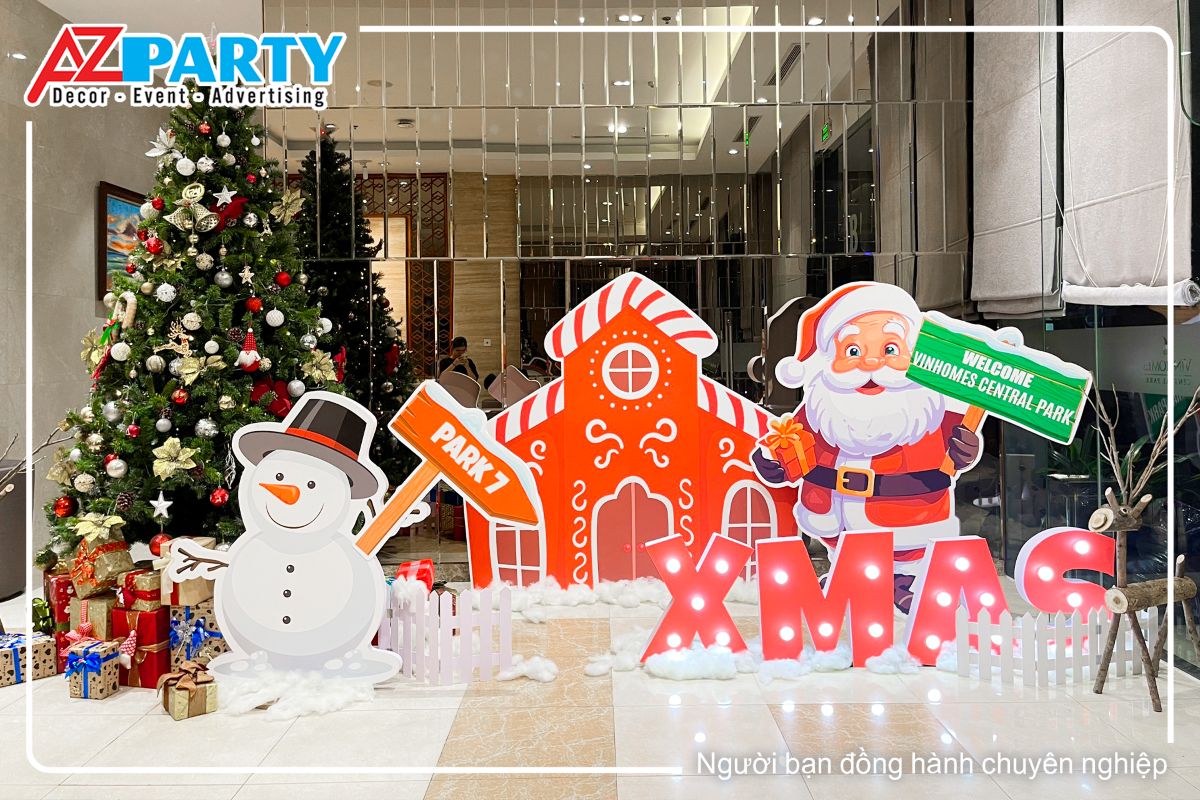 tiểu cảnh noel tại sảnh A với hình ảnh ngôi nhà gỗ, ông già noel và người tuyết cầm bằng welcome, ở góc còn lại là cây thông noel với những hộp quà được đặt ở dưới gốc cây