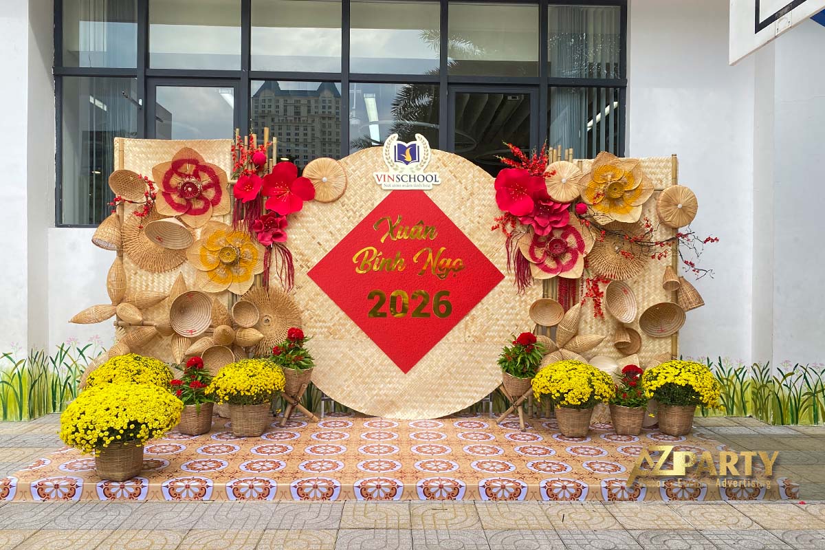 Tiểu cảnh tết ngoài trời tại Vinschool với phông nền mây tre đan, nón lá, truyền thống, hoa mai vàng, hoa đỏ