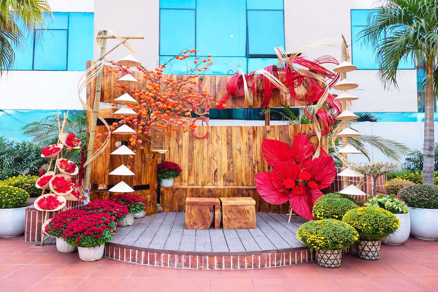 Mẫu tiểu cảnh Tết ngoài trời với phên tre uốn lượn và dây treo nón lá, hoa cúc vàng đỏ và bố cục truyền thống 