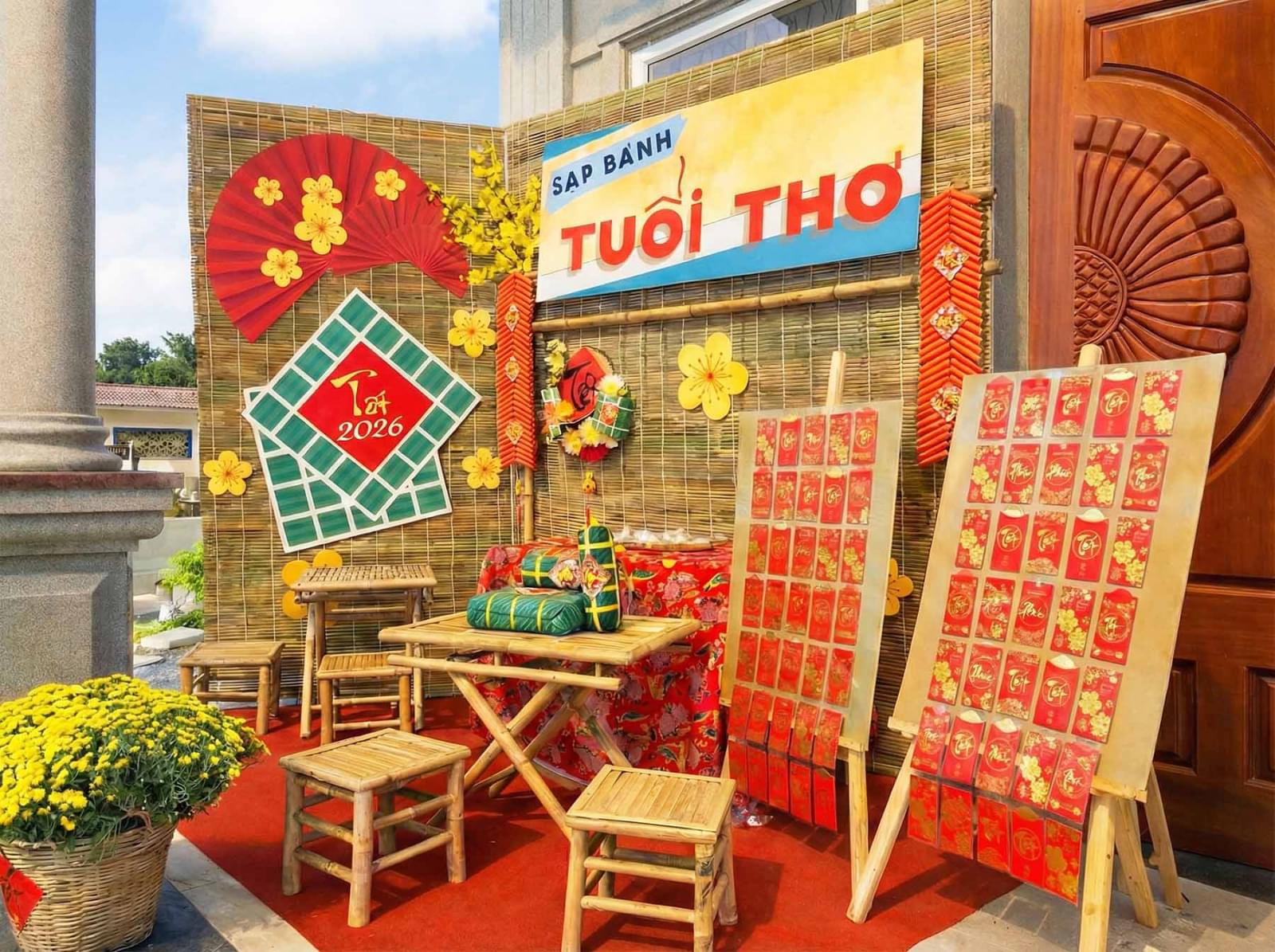 Tiểu cảnh trang trí Tết 2026 với concept sạp bánh tuổi thơ, phông tre mộc, quạt giấy đỏ, bánh chưng xanh, bàn ghế tre, bao lì xì đỏ 