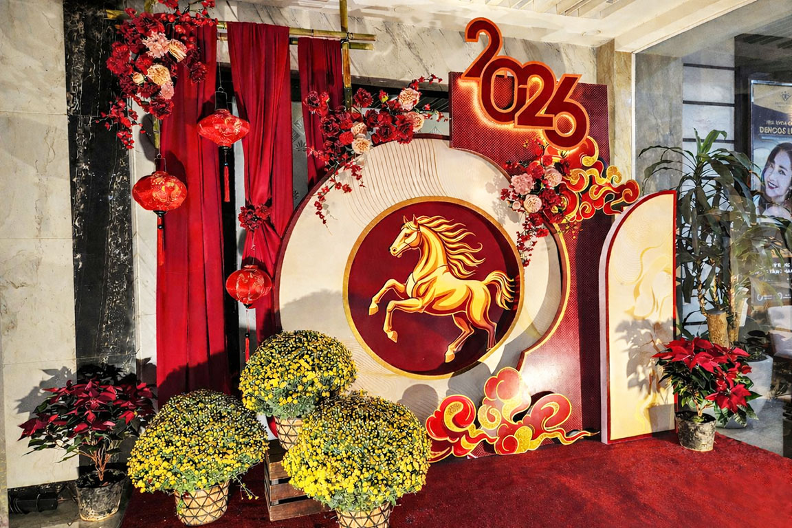 Tiểu cảnh trang trí Tết 2026 phong cách sang trọng với phông đỏ ánh kim, hình ngựa vàng cách điệu, rèm vải đỏ, đèn lồng và chậu hoa cúc vàng tạo điểm nhấn