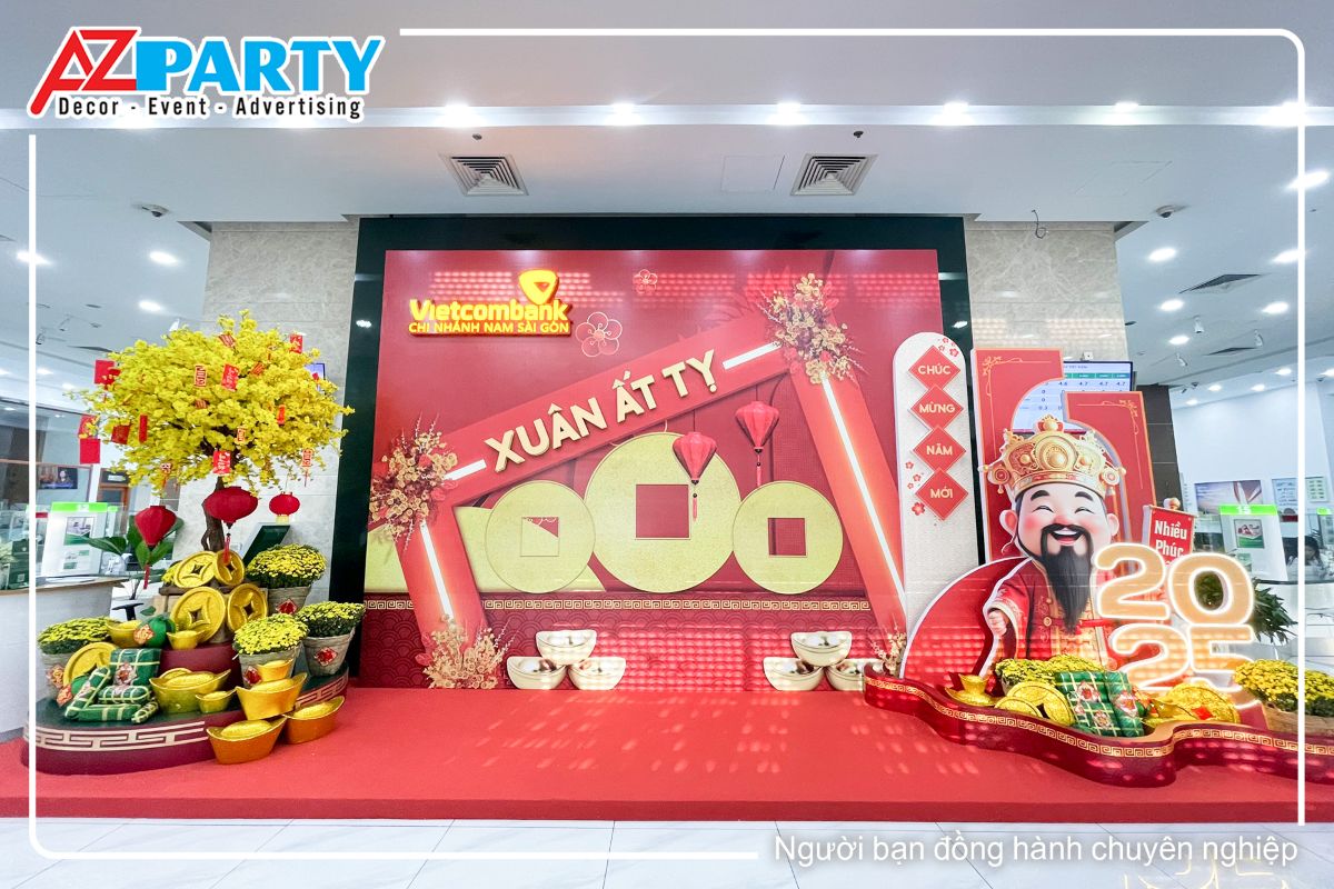 tiểu cảnh tết tại Ngân Hàng Vietcombank - Chi Nhánh Nam Sài Gòn, bên trái là mô hình ông thần tài bên phải là cây mai vàng, giữa tiểu cảnh là dòng chữ Xuân Ất Tỵ cùng đồng tiền xu vàng nổi  bật